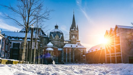 Foto de La famosa catedral gótica enorme del emperador Karl en Aquisgrán Alemania durante la temporada de invierno con nieve en Katschhof contra el cielo azul y el fondo del sol - Imagen libre de derechos
