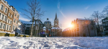 Foto de La famosa catedral gótica enorme del emperador Karl en Aquisgrán Alemania durante la temporada de invierno con nieve en Katschhof contra el cielo azul y el fondo del sol - Imagen libre de derechos