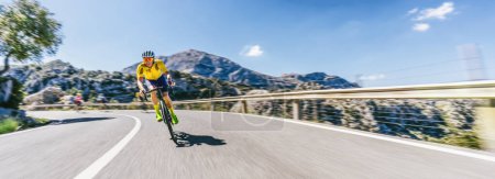 Téléchargez les photos : Mature Adulte sur un vélo de course escalade la colline à la mer Méditerranée paysage route côtière de montagne - montagnes de Mallorca - en image libre de droit