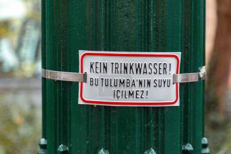 Trinkwasserverbotsschild in deutscher und türkischer Sprache an einem uralten Brunnen im Nikolaiviertel, einem Altstadtviertel von Berlin.