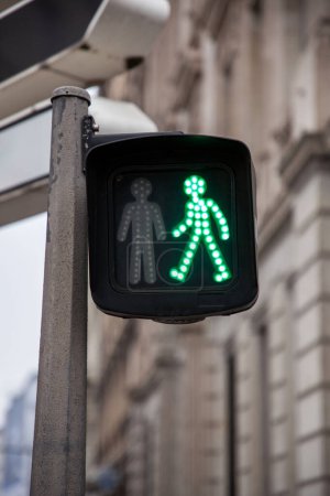 Pedestrian green light on a traffic light, abiding by the French and European traffic regulations, letting walking people crossing a crosswalk and a street in an urban environment