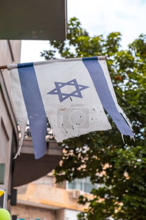 Ragged Israeli flag hanging on a building door in Tel Aviv, Israel.