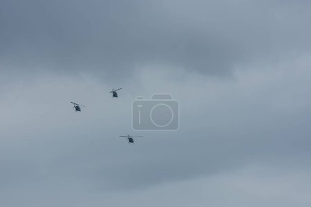 Foto de Tres helicóptero volando en el cielo gris con rainclouds - Imagen libre de derechos