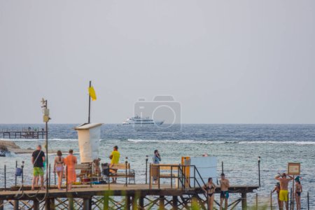 Photo for People on a jetty and a yacht at the horizon in egypt - Royalty Free Image