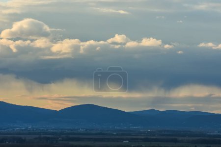 Photo for Rain under clouds over a landscape with mountains in the spring - Royalty Free Image