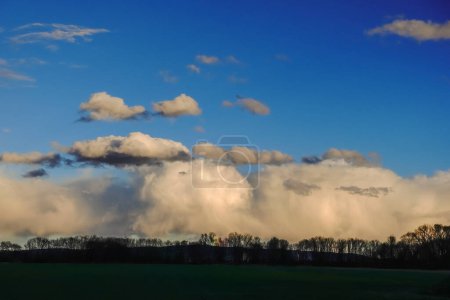 Photo for Dense clouds from a storm and dark blue sky in a flat landscape - Royalty Free Image