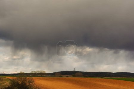Photo for Dense rain with dark clouds and storm over fields in the nature landscape - Royalty Free Image