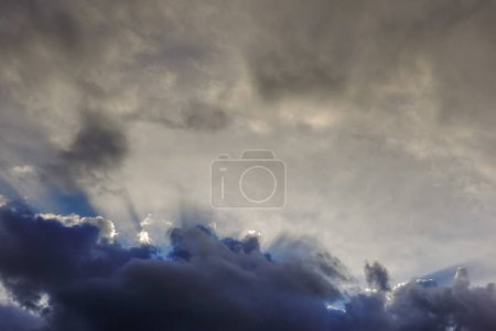 Photo for Sunrays from dense darke rain clouds on the sky after rain and storm in the spring - Royalty Free Image