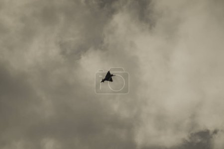 single loud slow flying fighter jet on a cloudy sky