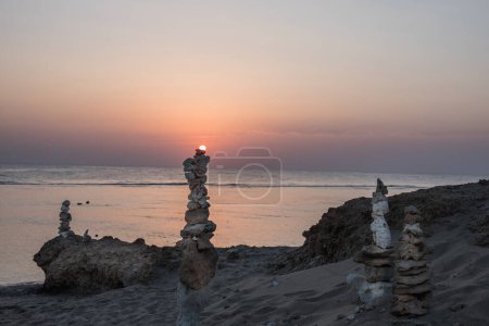 sol se encuentra en una torre apilada de corales en la playa durante el amanecer en Egipto