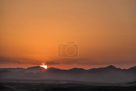 sun hiding behind mountains from the desert during sunset in egypt