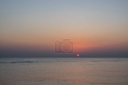 warm red sun at the horizon at the sea shortly after sunrise in egypt