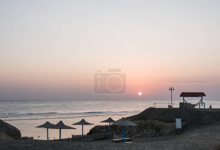 warmer Sonnenaufgang am Strand mit Sonnenschirmen und gemütlicher Hängematte am Morgen in Ägypten