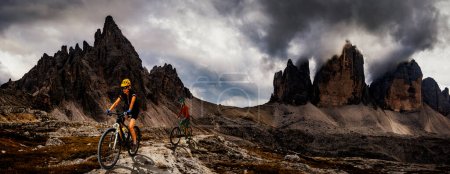 Photo for A man and woman ride electric mountain bikes in the Dolomites in Italy. Mountain biking adventure on beautiful mountain trails. - Royalty Free Image