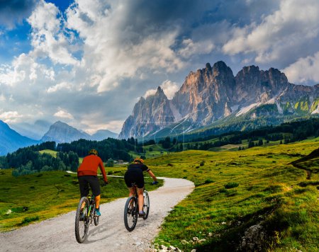 Foto de Un hombre y una mujer montan bicicletas eléctricas de montaña en los Dolomitas en Italia. Aventura en bicicleta de montaña en hermosos senderos de montaña. - Imagen libre de derechos