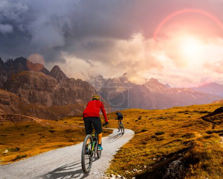 Foto de Un hombre y una mujer montan bicicletas eléctricas de montaña en los Dolomitas en Italia. Aventura en bicicleta de montaña en hermosos senderos de montaña. - Imagen libre de derechos