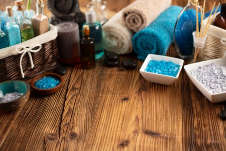 Téléchargez les photos : Spa and wellness concept. Bottles with bath and spa cosmetics, rolled up towels, bath salts and care products on wooden rustic paneling. - en image libre de droit
