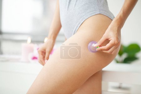 Photo for Woman getting anti-cellulite massage of leg with use of vacuum cans. - Royalty Free Image
