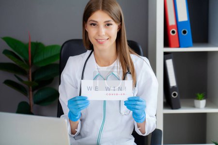 Téléchargez les photos : Femme médecin en uniforme tenant une enseigne en papier lettrage nous gagnons covid. - en image libre de droit