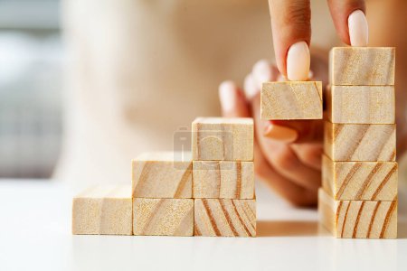 Photo for Woman hand arranging wood block stacking as step stair - Royalty Free Image