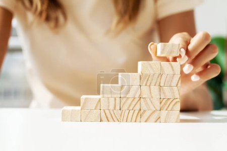 Foto de Mujer mano poner y apilar cubos de madera en blanco en el escritorio. - Imagen libre de derechos