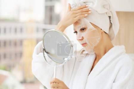 Téléchargez les photos : Femme gaie avec une serviette sur sa tête masque peau propre. - en image libre de droit