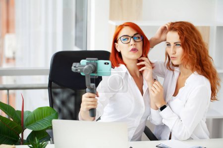 Foto de Dos mujeres de pelo rojo trabajan juntas en la oficina moderna. - Imagen libre de derechos