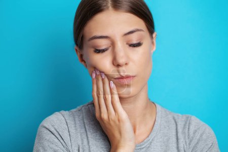 Woman suffering from tooth pain and touching cheek.
