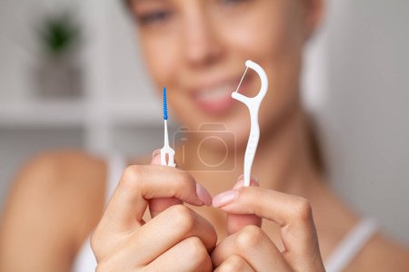 Téléchargez les photos : Femme utilisant de la soie dentaire pour nettoyer ses dents
. - en image libre de droit