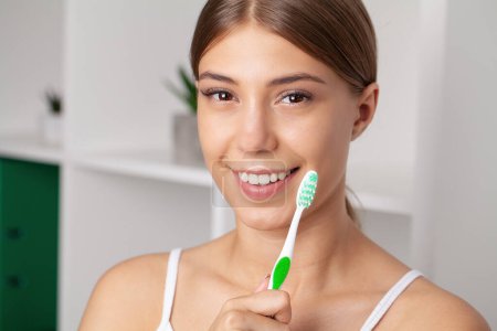 Happy Lady cepillando dientes con cepillo de dientes de pie en el baño.