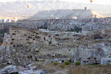 Photo for Cappadocia hot air baloon trip, Turkey. Tourists on board Hot air baloons are flying over Cappadocia traditional cave houses - Royalty Free Image