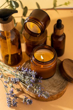 Téléchargez les photos : Soy candles in a glass jar. Aromatherapy. Burning candle and lavender. Wooden lid for jars. Beige background. Comfort and relaxation. Handmade. Home decor. - en image libre de droit