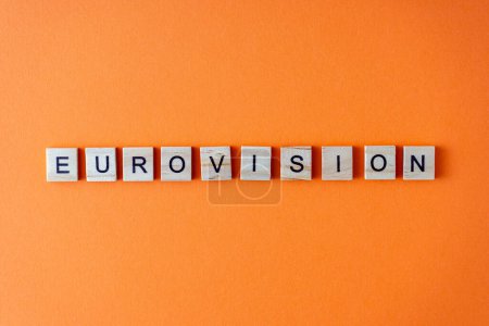 Téléchargez les photos : Mot Eurovision. La phrase est disposée en lettres de bois vue du dessus. Orange fond plat laïc - en image libre de droit