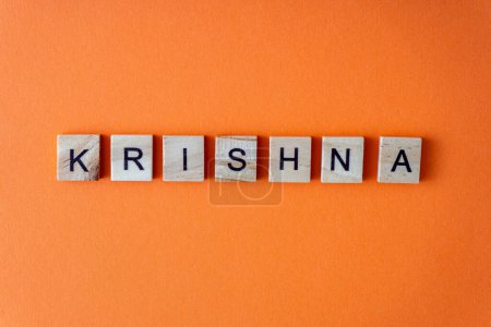 Foto de Palabra de Krishna. La frase se presenta en letras de madera vista superior. Fondo plano naranja lay - Imagen libre de derechos