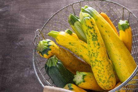 Photo for Yellow green leopard spotted zucchini. Vegetables on the table. vegetable marrow harvest. Food background. Fresh courgette, cropped summer squash. Picked courgettes. Still life in kitchen. - Royalty Free Image