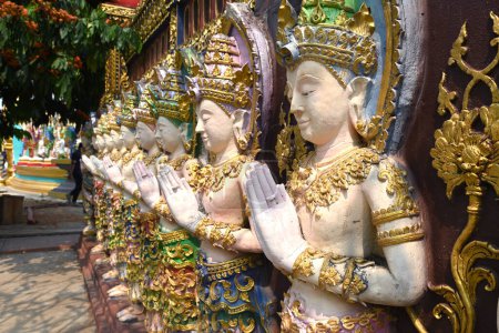 Photo for A group of deity statues standing in a row on a temple wall in Thailand - Royalty Free Image