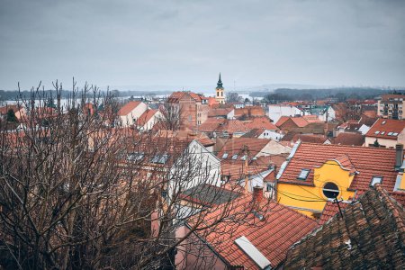 Téléchargez les photos : Vue du clocher et des toits carrelés du quartier de Zemun contre le ciel sombre et lunatique. Belgrade, Serbie - en image libre de droit
