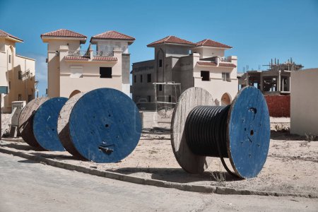 Cable on a reels at construction site. Wooden bobbins with electrical cable