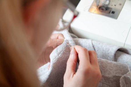 Téléchargez les photos : Femme en lunettes ouvre une couture sur un tissu avec une rippe couture - en image libre de droit