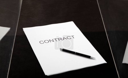 Foto de Contrato transparente. Un contrato impreso en papel y un bolígrafo se encuentra en una caja de vidrio close-u - Imagen libre de derechos