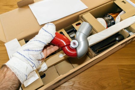 Photo for Paris, France - Jul 4, 2022: hand bandaged finger holding during unpacking new Up-Top-adaptor for modern wireless Dyson V12 Detect Slim Absolute Vacuum Cleaner powerful cordless colorful cyclonic dust - Royalty Free Image