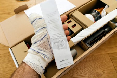 Photo for Paris, France - Jul 4, 2022: Man hand holding during unboxing quick start guide signed by James Dyson Engineer and Founder - modern wireless Dyson V12 Detect Slim Absolute Vacuum Cleaner powerful - Royalty Free Image