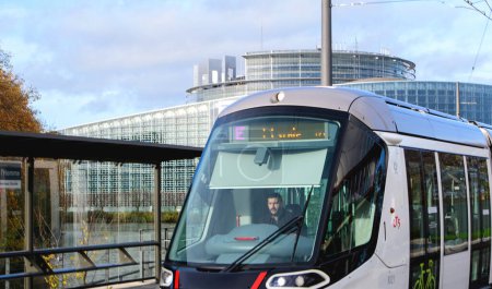 Foto de Estrasburgo, Francia - 22 de noviembre de 2022: Conductor masculino en el tranvía E que pasa por la ciudad con el edificio de la institución europea en segundo plano - Imagen libre de derechos