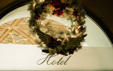 Téléchargez les photos : Insignes artistiques de signalisation d'hôtel sur verre avec couronne de Noël au-dessus - entrée au restaurant d'hôtel de luxe avec plafonds historiques peints - en image libre de droit