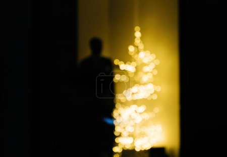 Foto de Silueta masculina alojada cerca de un abeto amarillo desenfocado: concepto de soledad durante las vacaciones de invierno, consumismo, etc. - Imagen libre de derechos