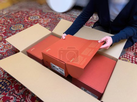 Photo for London, United Kingdom - Oct 21, 2022: Woman unboxing unpacking cardboard e-commerce internet order with three red Camper shoes - taking box from bigger one - Royalty Free Image