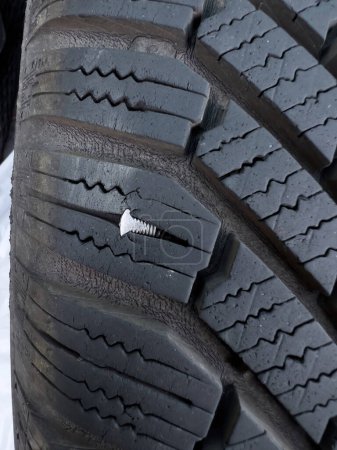 Photo for Button head needle metal nail stuck to puncture into wheel tire - winter flat tire flat - Royalty Free Image
