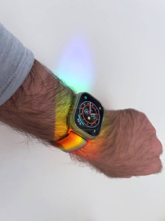 Foto de Koln, Alemania - Oct 12, 2022: POV mano masculina sosteniendo el nuevo Apple Watch Ultra con la luz del arco iris cayendo sobre el reloj inteligente portátil - Imagen libre de derechos