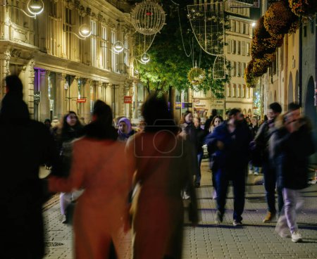 Foto de Strasbourg, France - Nov 25, 2022: Pedestrians people Silhouettes in motion walking in central Strasbourg at night during winter annual Christmas Market decorated - Imagen libre de derechos