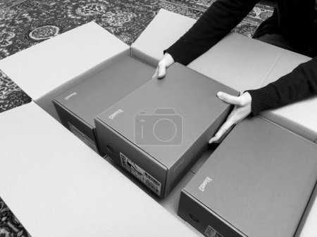 Téléchargez les photos : London, October 20, 2022: Woman hand taking from large cardboard smaller packages of new brand modern Camper box shoes - en image libre de droit